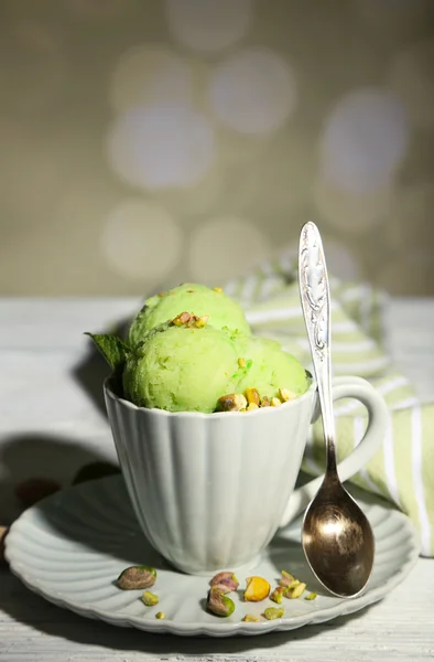 Smakelijke pistache ijs in cup op houten tafel, op lichte achtergrond — Stockfoto