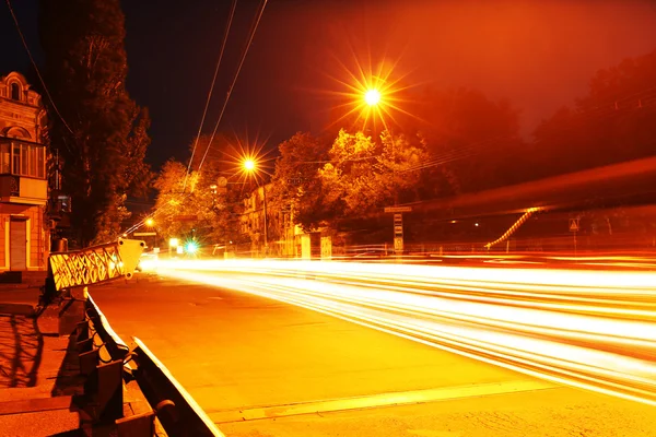 Переміщення автомобіля з розмитим світлом через місто вночі — стокове фото