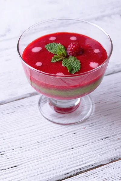 Smoothies aux fraises, aux kiwis et aux framboises dans un bol en verre sur fond de bois de couleur — Photo