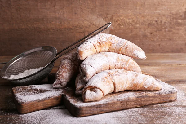 Tasty bagels with sugar powder, on wooden background — Stock Photo, Image