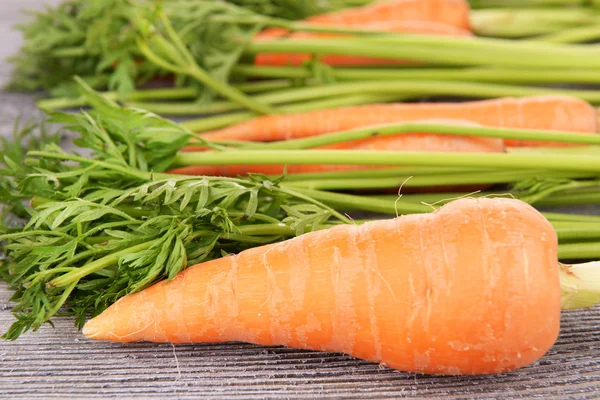 Fresh carrot with leaves on wooden background — Stock Photo, Image