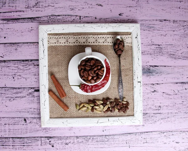 Holzrahmen mit weißem Becher, Kaffeekörnern und Gewürzen auf Holzgrund — Stockfoto