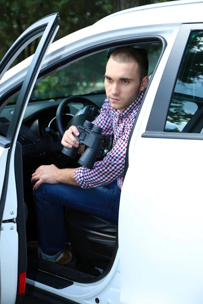 Man in de auto met een verrekijker — Stockfoto
