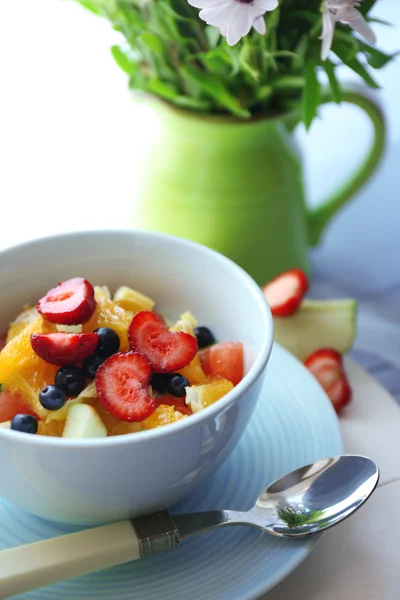 Útil ensalada de frutas caseras y flores en la mesa — Foto de Stock