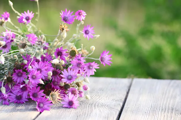 Lindas flores silvestres na mesa no fundo brilhante — Fotografia de Stock
