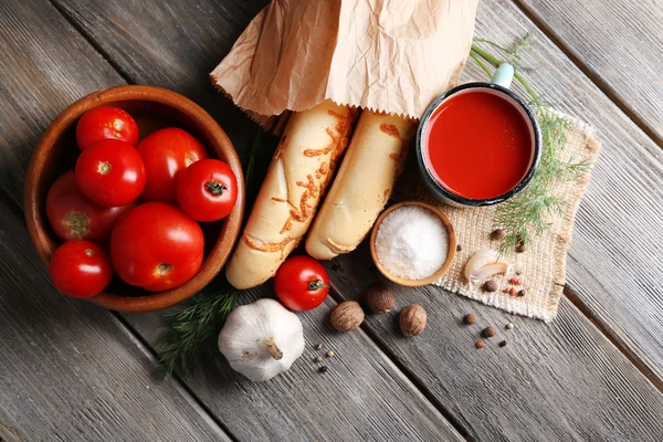 Jugo de tomate casero en taza de color, palitos de pan, especias y tomates frescos sobre fondo de madera —  Fotos de Stock