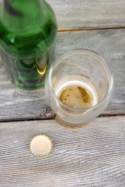 Botella y vaso con bebida fría, sobre fondo de madera — Foto de Stock