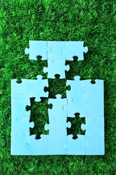 Puzzle de piezas sobre fondo de hierba verde. Concepto de espacio verde — Foto de Stock