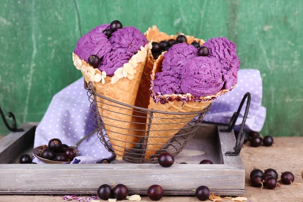 Gustoso gelato con bacche in coni di cialde su sfondo verde in legno — Foto Stock