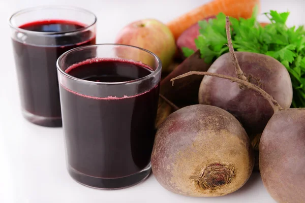 Los vasos de jugo de remolacha fresca y verduras en la tabla de cortar de cerca — Foto de Stock