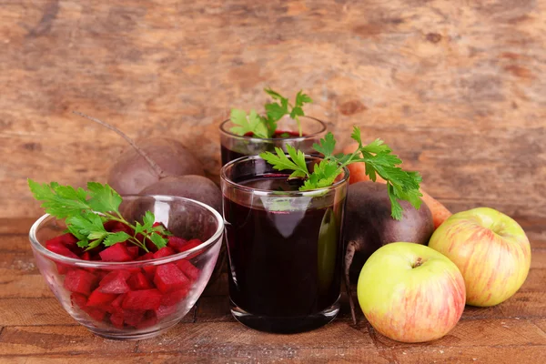 Vasos de jugo de remolacha fresca y verduras sobre fondo de madera — Foto de Stock