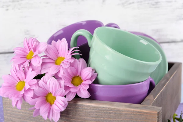 Platos brillantes con flores en cajón sobre fondo de madera —  Fotos de Stock