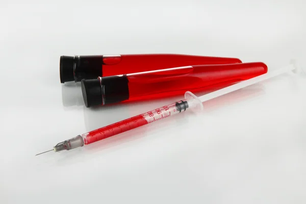 Test-tubes with plastic disposable syringe filled with blood isolated on white — Stock Photo, Image