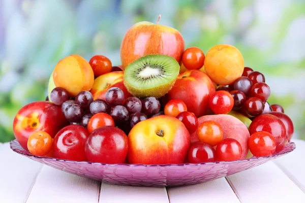 Surtido de frutas jugosas sobre mesa de madera, sobre fondo brillante — Foto de Stock