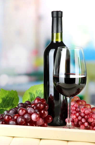 Uvas maduras, garrafa e copo de vinho na bandeja, sobre fundo brilhante — Fotografia de Stock