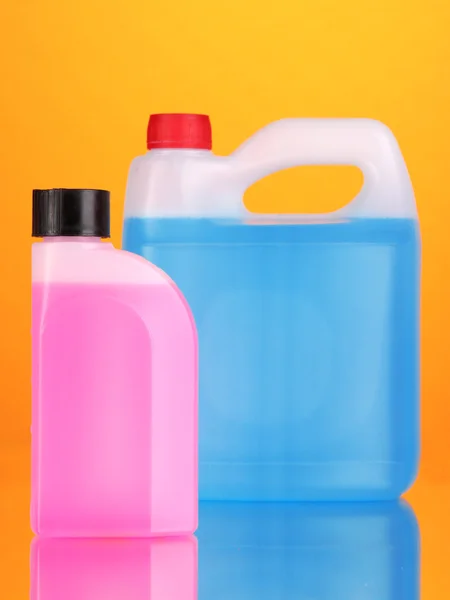 Líquidos azuis e rosa para carro em latas sobre fundo laranja — Fotografia de Stock