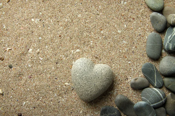 Grå sten i form av hjärta, på sand bakgrund — Stockfoto