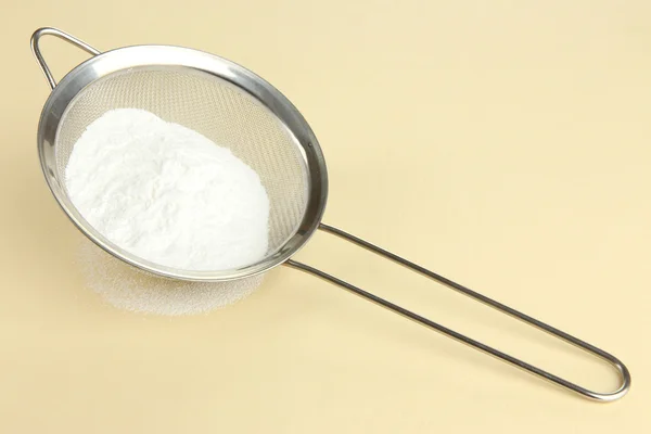 Powdered sugar in metal sieve on beige background — Stock Photo, Image