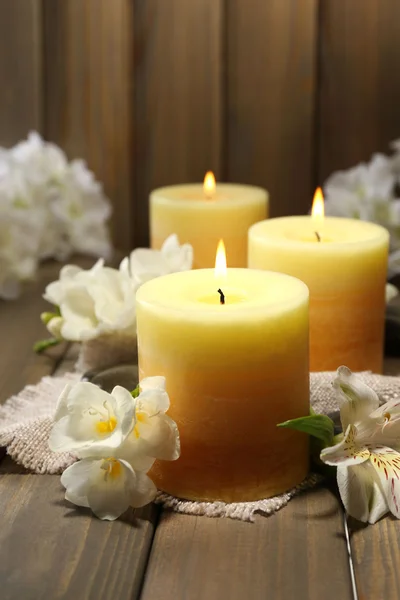 Hermosas velas con flores sobre fondo de madera — Foto de Stock