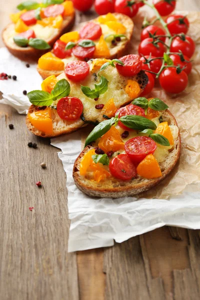 Sabrosa bruschetta con tomates, sobre una vieja mesa de madera —  Fotos de Stock