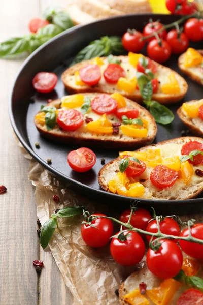 Smaker bruschetta med tomater på panne, på gammelt trebord – stockfoto