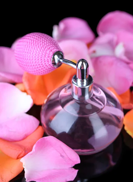 Perfume bottle with petals on black background — Stock Photo, Image