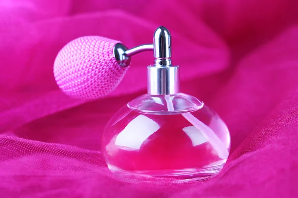 Frasco de perfume sobre fundo tecido rosa — Fotografia de Stock