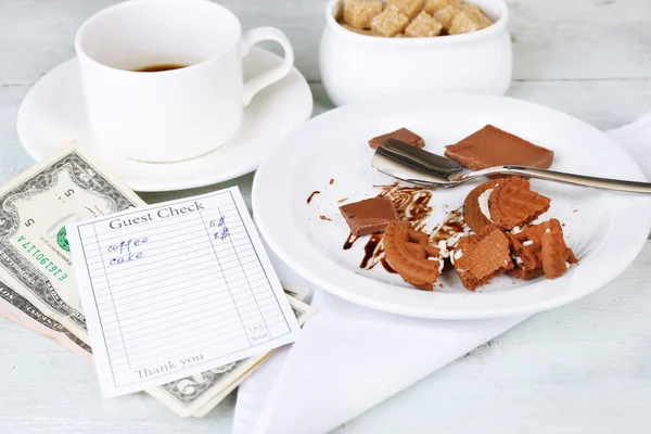 Чек, деньги и остатки еды и напитков на столе крупным планом — стоковое фото