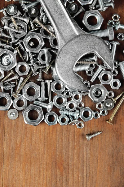 Llave en pernos, tornillos y tuercas en mesa de madera — Foto de Stock