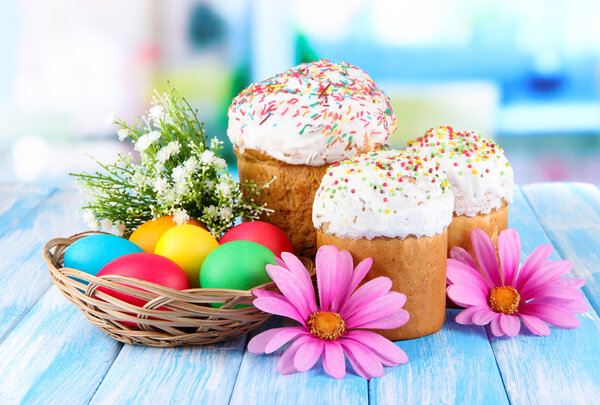 Sweet Easter cakes with colorful eggs on table in room
