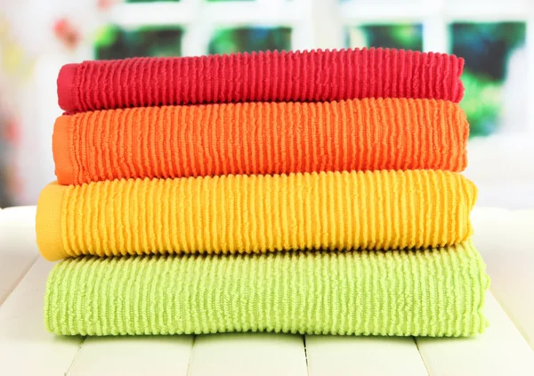 Bunte Handtücher auf Holztisch auf Fensterhintergrund — Stockfoto