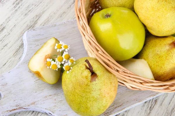 Pears in basket on board on wooden table — Stock Photo, Image