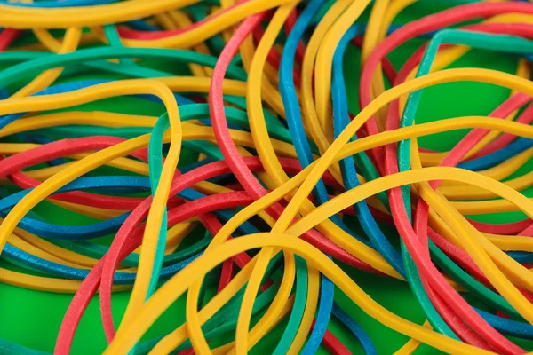 Colorful rubber bands on green background close-up — Stock Photo, Image