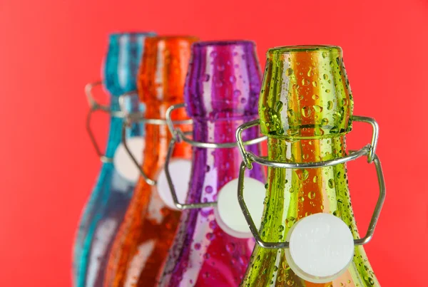Kolorowe butelki na czerwonym tle — Zdjęcie stockowe