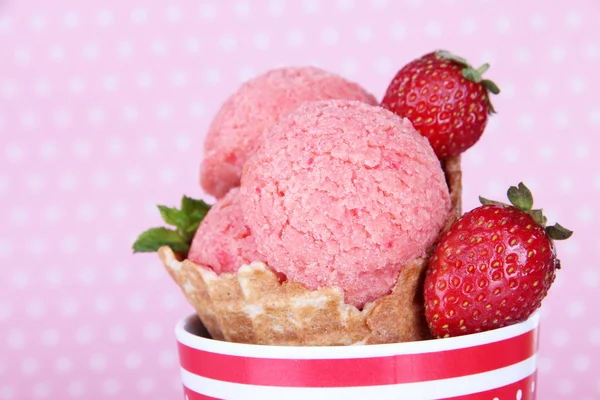 Crème glacée rose appétissante au cône de gaufre sur fond à pois — Photo