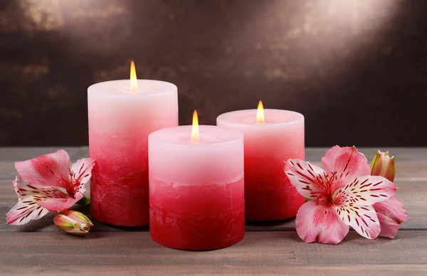 美丽的蜡烛，用鲜花上棕色背景表格 — 图库照片