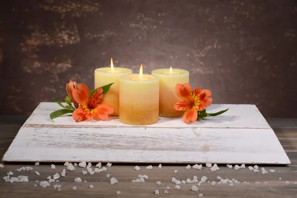 美丽的蜡烛，用鲜花上棕色背景表格 — 图库照片