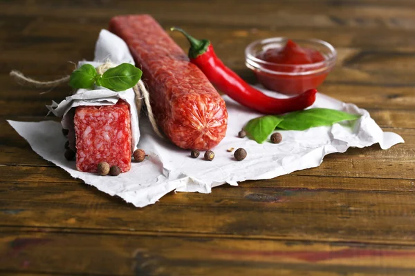 Välsmakande salami korv och kryddor på trä bakgrund — Stockfoto