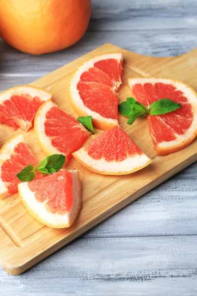 Ripe grapefruits on cutting board, on wooden table, on light background — Stock Photo, Image