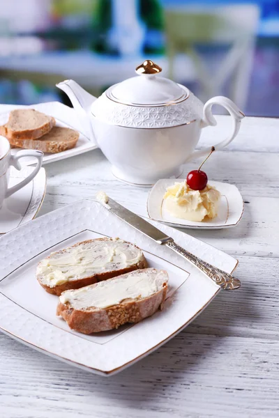 Vers brood en eigengemaakte boter op plaat op houten tafel, lichte achtergrond — Stockfoto