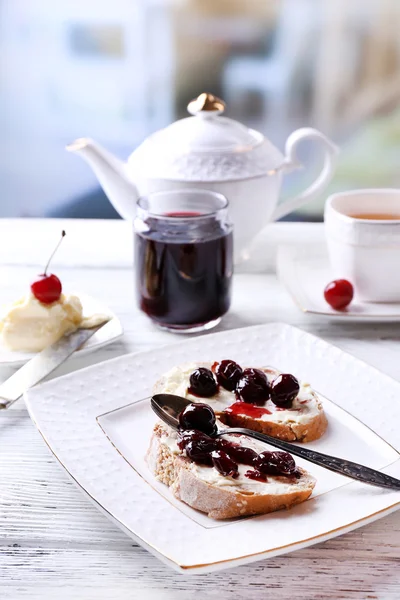 Pan fresco con mermelada de cereza y mantequilla casera en plato sobre mesa de madera, sobre fondo brillante —  Fotos de Stock