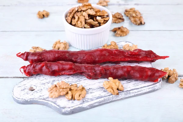 Sabrosos dulces orientales (churchkhela) y nueces frescas, sobre fondo de madera —  Fotos de Stock