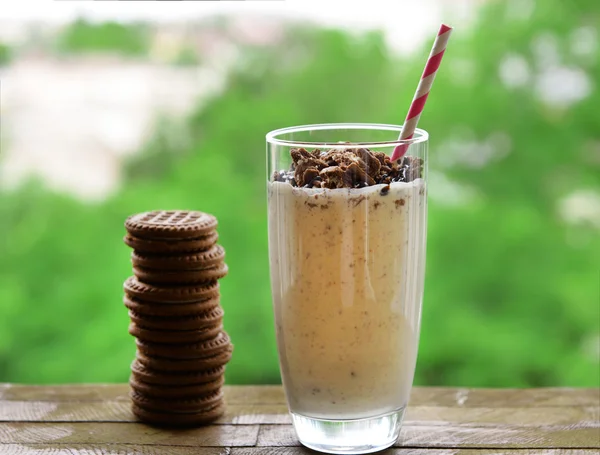 Mléko koktejl ve skle a čokoládové sušenky na stůl na přírodní pozadí — Stock fotografie