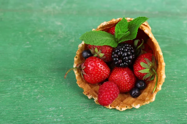 Different ripe berries in sugar cone, on green wooden background — Stock Photo, Image