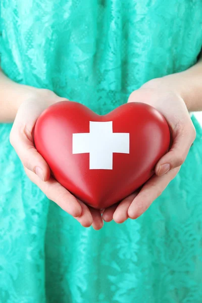 Red heart with cross sign n hands — Stock Photo, Image