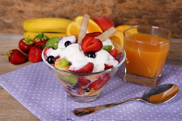 Салат из свежих фруктов с мороженым в миске и соком на деревянном фоне — стоковое фото