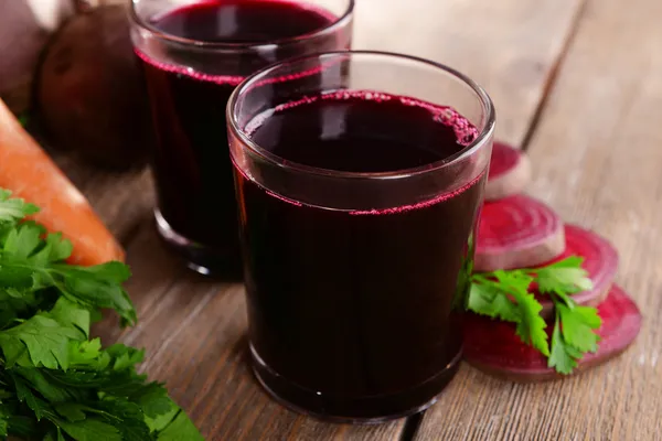 Verres de jus de betterave et légumes frais sur fond en bois — Photo