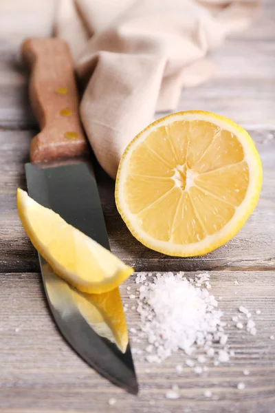 Stillleben mit frischer Zitrone, Messer und Salz auf altem Holztisch — Stockfoto