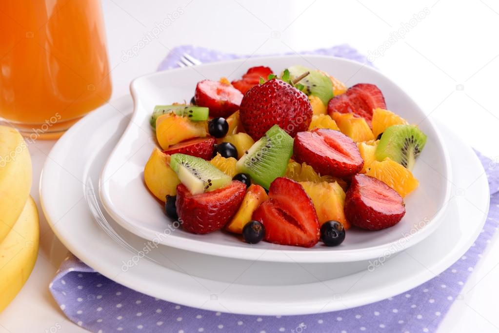 Fresh fruits salad on plate on napkin close up