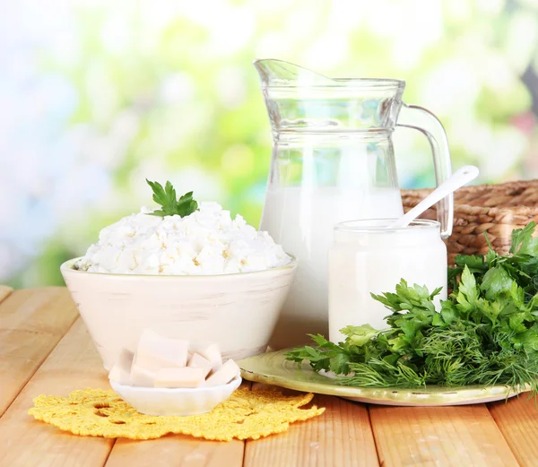 Färska mjölkprodukter med gröna på träbord på naturliga bakgrund — Stockfoto